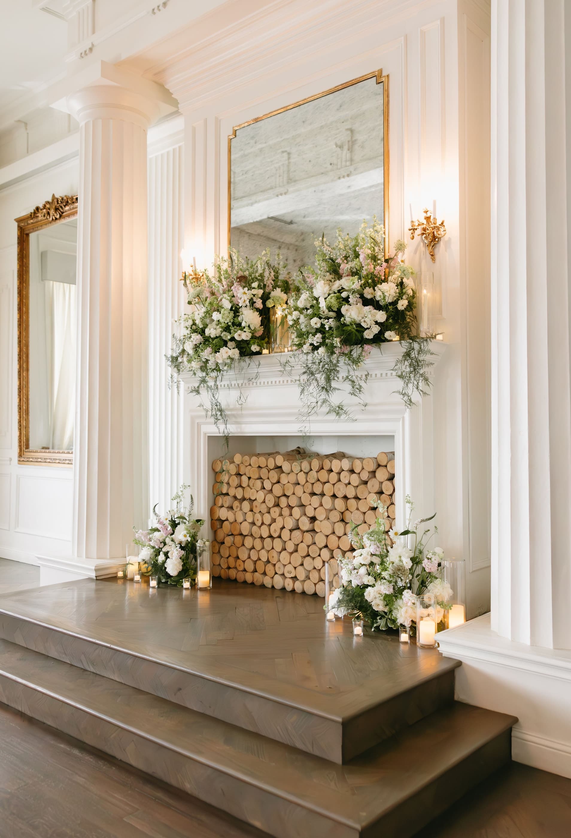 A lush white and blush floral installation across a white marble mantel
