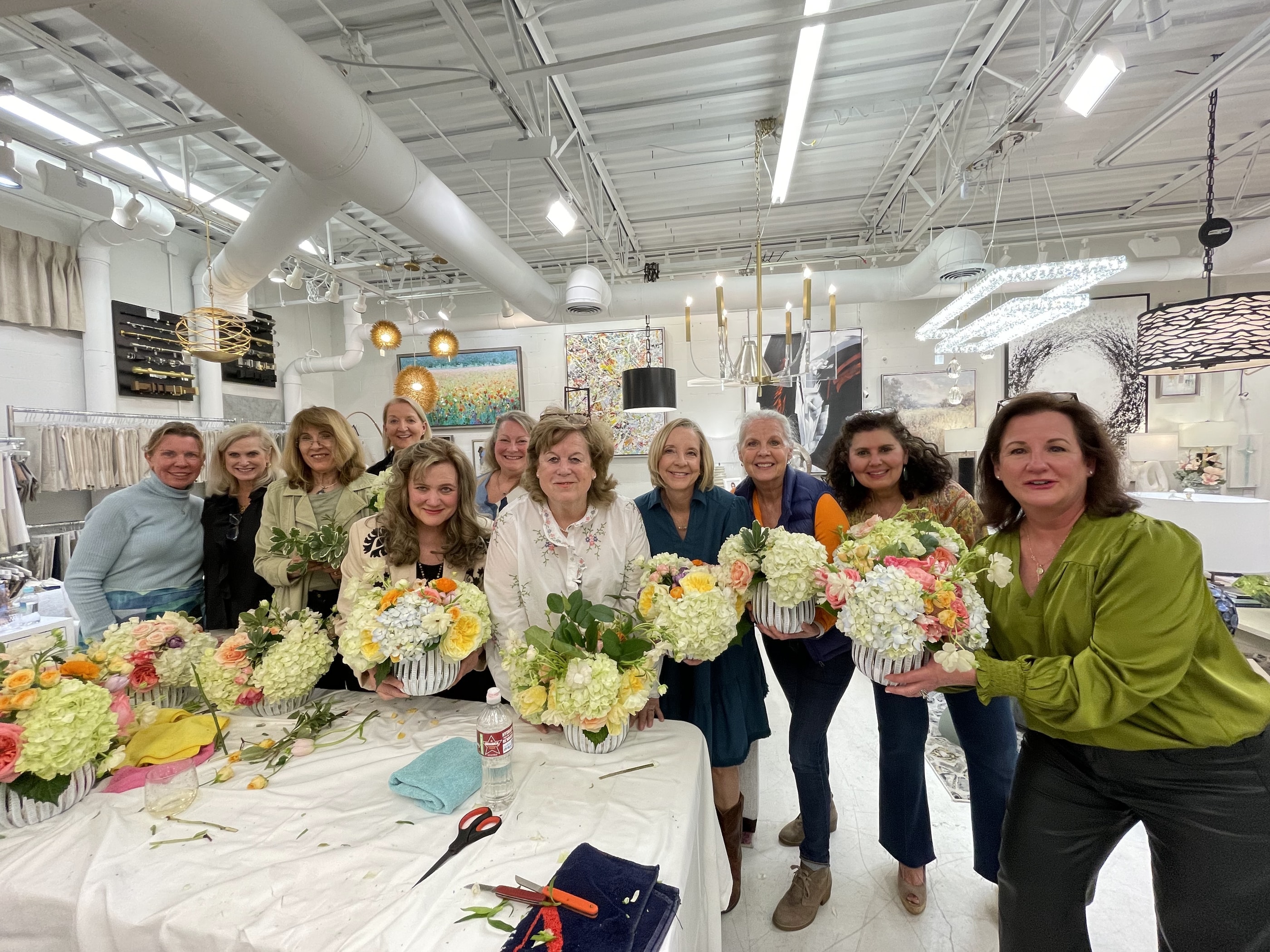 Workshop guests holding up the arrangements they built at the end of a class